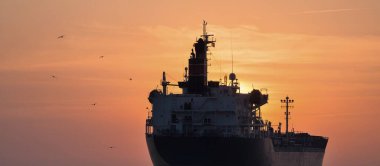 Büyük bir kargo gemisi gün batımında Baltık Denizi 'ne açılacak. Yumuşak altın güneş ışığı. Deniz manzarası kavramı. Yelkenliden panoramik görüntü. Nakliye, denizcilik, lojistik.