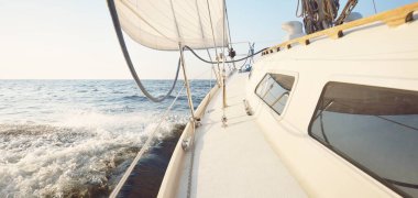 Günbatımında beyaz yelkenli tekneyle denize açılacak. Fırtınadan sonra gökyüzü açık. Güverteden pruvaya, direğe, yelkenlere bakın. Ulaşım, seyahat, gezi, spor, eğlence, boş zaman aktivitesi, yarış, yelkenli yarışı