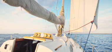 Günbatımında beyaz yelkenli tekneyle denize açılacak. Fırtınadan sonra gökyüzü açık. Güverteden pruvaya, direğe, yelkenlere bakın. Ulaşım, seyahat, gezi, spor, eğlence, boş zaman aktivitesi, yarış, yelkenli yarışı