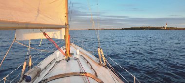Günbatımında beyaz yelkenli tekneyle denize açılacak. Fırtınadan sonra gökyüzü açık. Güverteden pruvaya, direğe, yelkenlere bakın. Ulaşım, seyahat, gezi, spor, eğlence, boş zaman aktivitesi, yarış, yelkenli yarışı