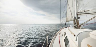 Günbatımında beyaz yelkenli tekneyle denize açılacak. Fırtınadan sonra gökyüzü açık. Güverteden pruvaya, direğe, yelkenlere bakın. Ulaşım, seyahat, gezi, spor, eğlence, boş zaman aktivitesi, yarış, yelkenli yarışı