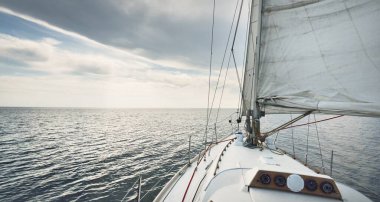 Günbatımında beyaz yelkenli tekneyle denize açılacak. Fırtınadan sonra gökyüzü açık. Güverteden pruvaya, direğe, yelkenlere bakın. Ulaşım, seyahat, gezi, spor, eğlence, boş zaman aktivitesi, yarış, yelkenli yarışı