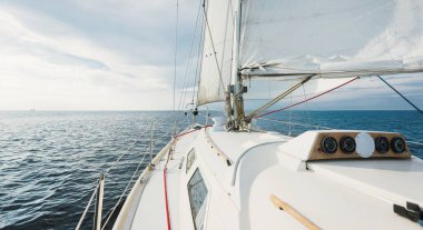 Günbatımında beyaz yelkenli tekneyle denize açılacak. Fırtınadan sonra gökyüzü açık. Güverteden pruvaya, direğe, yelkenlere bakın. Ulaşım, seyahat, gezi, spor, eğlence, boş zaman aktivitesi, yarış, yelkenli yarışı