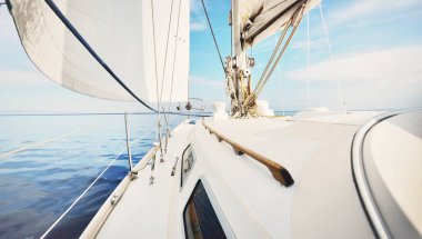 Günbatımında beyaz yelkenli tekneyle denize açılacak. Fırtınadan sonra gökyüzü açık. Güverteden pruvaya, direğe, yelkenlere bakın. Ulaşım, seyahat, gezi, spor, eğlence, boş zaman aktivitesi, yarış, yelkenli yarışı