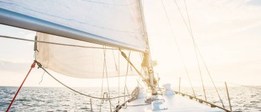 Günbatımında beyaz yelkenli tekneyle denize açılacak. Fırtınadan sonra gökyüzü açık. Güverteden pruvaya, direğe, yelkenlere bakın. Ulaşım, seyahat, gezi, spor, eğlence, boş zaman aktivitesi, yarış, yelkenli yarışı