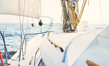 Günbatımında beyaz yelkenli tekneyle denize açılacak. Fırtınadan sonra gökyüzü açık. Güverteden pruvaya, direğe, yelkenlere bakın. Ulaşım, seyahat, gezi, spor, eğlence, boş zaman aktivitesi, yarış, yelkenli yarışı