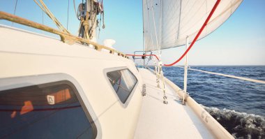 Günbatımında beyaz yelkenli tekneyle denize açılacak. Fırtınadan sonra gökyüzü açık. Güverteden pruvaya, direğe, yelkenlere bakın. Ulaşım, seyahat, gezi, spor, eğlence, boş zaman aktivitesi, yarış, yelkenli yarışı