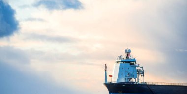 Büyük bir kargo gemisi gün batımında Baltık Denizi 'ne açılacak. Yumuşak altın güneş ışığı. Deniz manzarası kavramı. Yelkenliden panoramik görüntü. Nakliye, denizcilik, lojistik.