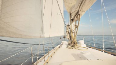 Günbatımında beyaz yelkenli tekneyle denize açılacak. Fırtınadan sonra gökyüzü açık. Güverteden pruvaya, direğe, yelkenlere bakın. Ulaşım, seyahat, gezi, spor, eğlence, boş zaman aktivitesi, yarış, yelkenli yarışı