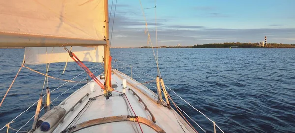 Günbatımında beyaz yelkenli tekneyle denize açılacak. Fırtınadan sonra gökyüzü açık. Güverteden pruvaya, direğe, yelkenlere bakın. Ulaşım, seyahat, gezi, spor, eğlence, boş zaman aktivitesi, yarış, yelkenli yarışı