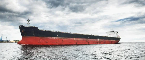 Large cargo ship sailing in the Baltic sea. Panoramic view from the sailing boat. Freight transportation, nautical vessel, logistics