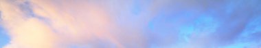 Açık mavi gökyüzü, gün batımında parlayan pembe ve altın bulutlar. Dramatik bulut manzarası. Yumuşak güneş ışığı, gece yarısı güneşi. Sanat, meteoroloji, cennet, umut, barış, resimli panoramik manzara