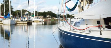 Mavi yelkenli bir yelkenli yat limanındaki bir rıhtıma demirlemiş. Tatiller, ulaşım, spor, eğlence, turizm, seyahat, liman