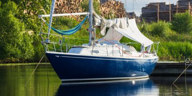 Mavi yelkenli bir yelkenli yat limanındaki bir rıhtıma demirlemiş. Tatiller, ulaşım, spor, eğlence, turizm, seyahat, liman