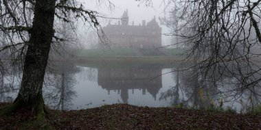 Orman parkında gölet ve kale. Jaunmoku pils, Letonya. Sis. Atmosferik sonbahar manzarası. Sessizlik, yalnızlık, melankolik kavramlar. Panoramik görünüm