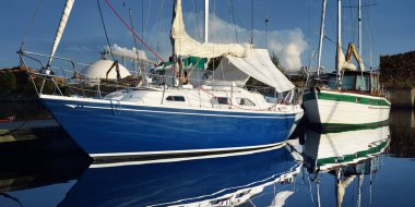 Mavi yelkenli bir yelkenli yat limanındaki bir rıhtıma demirlemiş. Tatiller, ulaşım, spor, eğlence, turizm, seyahat, liman