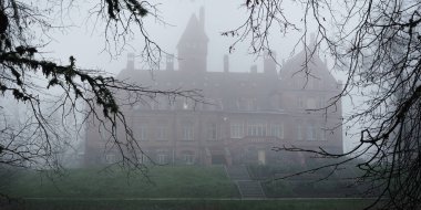 Orman parkında gölet ve kale. Jaunmoku pils, Letonya. Sis. Atmosferik sonbahar manzarası. Sessizlik, yalnızlık, melankolik kavramlar. Panoramik görünüm
