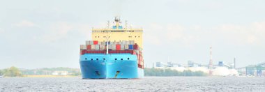 Norfolk limanından ayrılan büyük bir yük konteynırı gemisi, yakın plan. Bulutlu mavi gökyüzü. Virginia, ABD. Nakliye, lojistik, endüstri, küresel iletişim teması