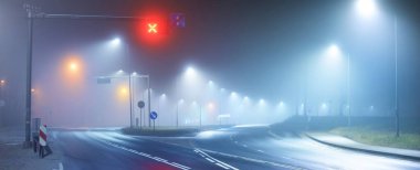 Gece sisli bir ortamda bomboş bir otoyol. Sokak lambaları ve yol işaretleri yakın. Karanlık şehir manzarası, şehir manzarası. Riga, Letonya. Tehlikeli sürüş, hız, özgürlük, konsept görüntü