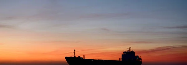 日没時に灯台近くを航行する大型貨物船 カラフルな雲の風景 リガ湾 バルト海 ラトビア 国際通信 物流をテーマに — ストック写真