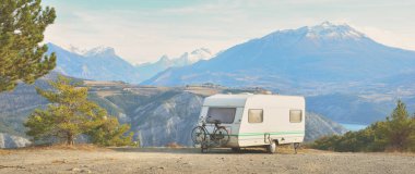 Lac de Serre-Poncon Gölü yakınlarındaki Fransız Alpleri manzaralı bir dağın tepesine park edilmiş karavan karavanı. Ulaşım, karavan, karavan, yol gezisi, kamp, turizm, eğlence, yaşam tarzı