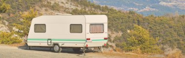 Lac de Serre-Poncon Gölü yakınlarındaki Fransız Alpleri manzaralı bir dağın tepesine park edilmiş karavan karavanı. Ulaşım, karavan, karavan, yol gezisi, kamp, turizm, eğlence, yaşam tarzı
