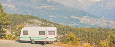 Lac de Serre-Poncon Gölü yakınlarındaki Fransız Alpleri manzaralı bir dağın tepesine park edilmiş karavan karavanı. Ulaşım, karavan, karavan, yol gezisi, kamp, turizm, eğlence, yaşam tarzı