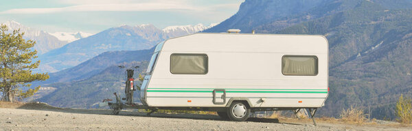 Караван-трейлер припаркован на вершине горы с видом на французские Альпы возле озера Лак де Серр-Понкон. Транспорт, RV, motorhome, road trip, camping, tourism, recreation, lifestyle