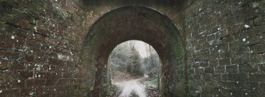 Orman parkından geçen bir yol, Lorraine, Fransa 'da eski ve karanlık bir tuğla tünel. Atmosferik panoramik manzara. Seyahat yerleri, tatiller, turizm, tarih, geçmiş