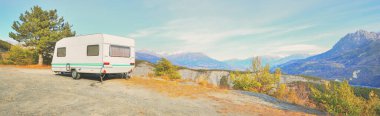 Lac de Serre-Poncon Gölü yakınlarındaki Fransız Alpleri manzaralı bir dağın tepesine park edilmiş karavan karavanı. Ulaşım, karavan, karavan, yol gezisi, kamp, turizm, eğlence, yaşam tarzı