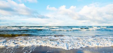 Kumlu bir sahilden (kum tepeleri) Baltık denizinin panoramik görüntüsü. Koyu bulutlu dramatik bir gökyüzü. Dalgalar, su sıçramaları. Idyllic deniz manzarası. Sıcak kış havası, iklim değişikliği, doğa