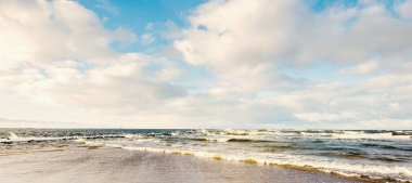 Kumlu bir sahilden (kum tepeleri) Baltık denizinin panoramik görüntüsü. Koyu bulutlu dramatik bir gökyüzü. Dalgalar, su sıçramaları. Idyllic deniz manzarası. Sıcak kış havası, iklim değişikliği, doğa