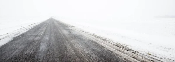 吹雪の中で雪に覆われたフィールドを介してカントリーロード 大気の冬の風景 氷の砂漠 — ストック写真