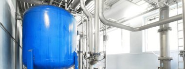 Büyük endüstriyel arıtma tesisi ve kazan dairesi. Parlak çelik metal borular ve mavi pupms ve vanalar.