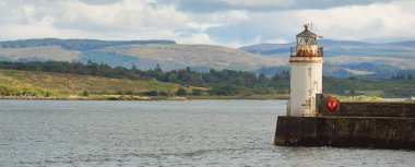 Küçük bir Ardrishaig köyünün kayalık kıyıları ve ormanlarının panoramik manzarası. Gezinti güvertesi ve deniz fenerine yakın çekim. Loch Fyne, Crinan Kanalı, Argyll ve Bute, İskoçya, İngiltere