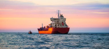 Büyük bir kargo gemisi gün batımında yola çıkıyor. Baltık Denizi. Panoramik manzara. Yük taşımacılığı, lojistik, küresel iletişim, ekonomi, ticaret, sanayi