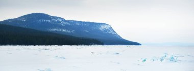 Gün batımında Kandalaksha Körfezi 'nin buz basıncı sırtı. Parlayan bulutlar. Arka planda Kola Yarımadası 'nın dağları ve kozalaklı ormanları var. Beyaz deniz, Kutup dairesi, Karelia, Rusya
