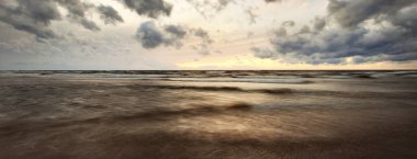 Göz kamaştırıcı gün batımı gökyüzü, Baltık Denizi, Danimarka. Fırtına dalgaları, renkli bulutların arasından geçen altın akşam güneşi. Uzun pozlama