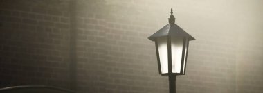 Gece sisli bir gecede sokak lambası ve kale duvarı. Gizemli ışık. Atmosferik kentsel sahne, panoramik görüntü
