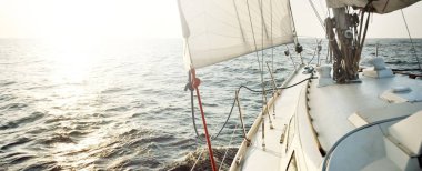 Gün batımında açık denizde yelkenli yelkenli yelkenli. Gökyüzü açık. Güverteden pruvaya bir manzara, direk, yelkenler. Ulaşım, seyahat, gezi, spor, eğlence, boş zaman aktivitesi, yarış, yelkenli yarışı