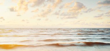 Gök gürültülü fırtınadan sonra denizin üstünde destansı, parlak, altın renkli günbatımı bulutları. Dramatik bir gökyüzü. Dalgalar ve su dokuya sıçrar. Idyllic deniz manzarası. Kavramsal görüntü, uzun pozlama. Resim gibi bir manzara.