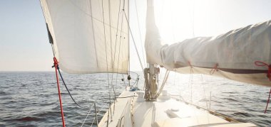 Gün batımında açık denizde yelkenli yelkenli yelkenli. Gökyüzü açık. Güverteden pruvaya bir manzara, direk, yelkenler. Ulaşım, seyahat, gezi, spor, eğlence, boş zaman aktivitesi, yarış, yelkenli yarışı