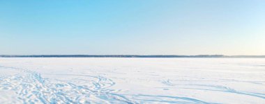 Güneşli bir günde donmuş orman gölü, donmakta olan ağaçlar, taze kar altında kayak ve insan izleri. Idyllic kırsal kesim. Açık mavi gökyüzü. Doğa, ekoloji, iklim değişikliği, küresel ısınma, Noel temaları
