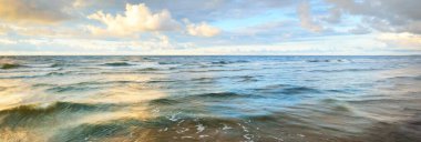 Gün batımında fırtınadan sonra Baltık Denizi kıyısında parlayan kümülüs bulutlarıyla açık bir gökyüzü. Dramatik bulut manzarası. Yumuşak altın güneş ışığı. Resimli bir manzara var. Hava kararsız. Uzun pozlama