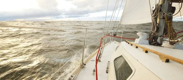 日落时 游艇在开阔的海面上航行 从甲板到船头 桅杆和船帆的近景 多灾多难的天空 金色的云彩 冬天的旋风 恶劣的天气 史诗般的海景挪威北海 — 图库照片