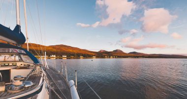 Günbatımında Jura adasının kayalık kıyılarında seyir halindeki ahşap meşe güvertesiyle donatılmış modern bir yat. Inner Hebrides, İskoçya, İngiltere. Spor, eğlence, gezi, seyahat yerleri.