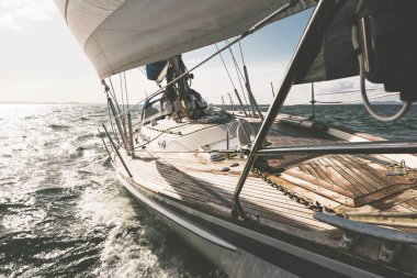 Dalgalarda yarışan ahşap meşe güverteli modern yatla donatılmış. Güverteden pruvaya bir manzara. Su, yakından sıçrıyor. Islay Adası, Inner Hebrides, İskoçya, İngiltere. Spor ve eğlence.