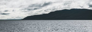 Dramatik gökyüzü altında Tarbert 'in kayalık kıyılarının panoramik manzarası. İskoçya, İngiltere. Seyahat yerleri, ulusal dönüm noktası, eğlence, eko turizm, tatiller, macera, keşif