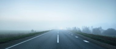 Gece sisli bir havada boş otobanın panoramik görüntüsü. Ay ışığı, temiz gökyüzü. Gün doğumu. Avrupa. Ulaşım, lojistik, seyahat, yolculuk, özgürlük, sürüş. Kırsal alan