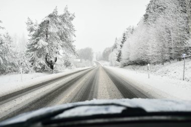 Boş otoyol (asfalt yol) karla kaplı ormanın içinden, kırsal alanda. Arabadan bak. Avrupa. Doğa, Noel tatilleri, uzak yerler, kış lastikleri, tehlikeli sürüş konsepti